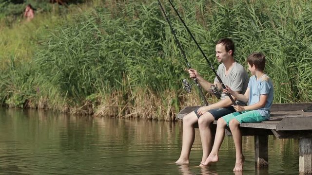 Family fishing with rods by the pond in summer