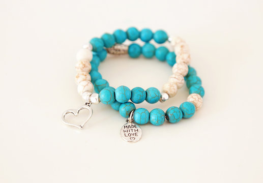 turquoise gemstone bracelets with silver charms isolated on white