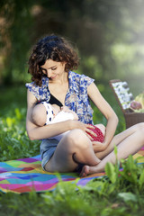 Naklejka na ściany i meble Young mother breast feeding a baby in the park