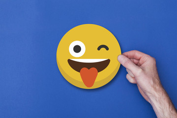 Male hand holding a emoji emoticon smiley head icon