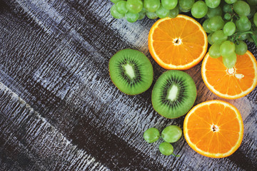 Grape, kiwi and orange on the dark background. Copy space