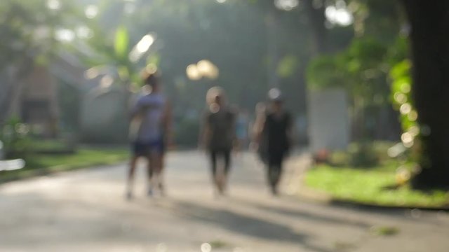 Slow motion and out of focus. Unidentified people running and walking in a park with sunshine. Ho Chi Minh city, Viet Nam