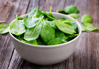 Fresh spinach leafs with drops in a bowl on a rustic wooden table
