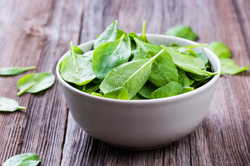 Fresh spinach leafs with drops in a bowl on a rustic wooden table