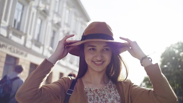 Cute woman walking in city while putting hat on