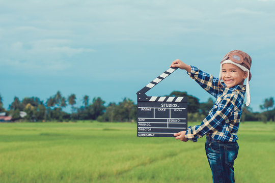 Kid Playing Film Clapper Board Against Summer Sky Background. Film Director Concept.