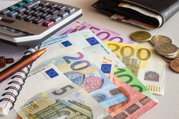 Euro paper money and coins with wallet and calculator on the table. Money counting.