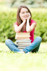 happy student girl sitting near pile of books