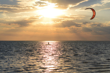 Kitesurfers ride on the waves at sunset