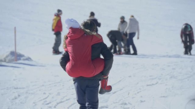 Boy takes girl on the men walking on the snow in a sky station