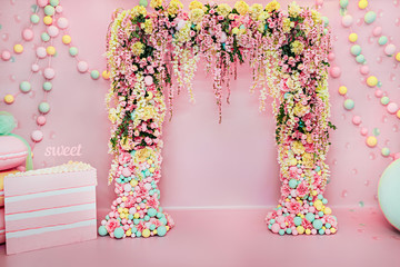 Wedding arch indoors. Festive decorations with flowers and colorful balloons on pink background