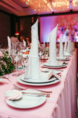 Beautifully organized event, glasses at served festive white table ready. Banquet, wedding decor. Cutlery and crockery