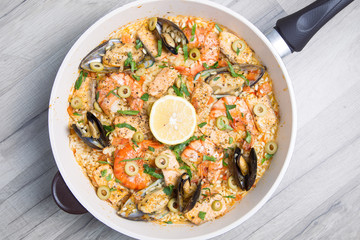 Paella with tiger shrimps, mussels, salmon and olives. Traditional Spanish dish.