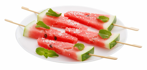 Slices of watermelon with stick on white plate isolated on white background. It looks like ice cream. Decorated with mint leaves and coconut.