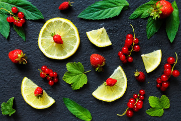 Fruit berry pattern from strawberry strawberries red currant leaves mint and lemon on a dark background to copy space