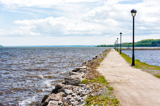 Portneuf, Quebec, Canada pier by harbor marina in Saint-Laurent or Saint Lawrence river with rocky path, benches and nobody