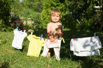 Fototapeta premium fun happy baby girl to wash clothes and laughs in the meadow on a sunny summer day.