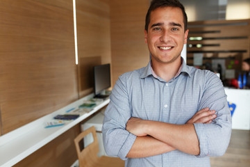 Portrait of young male office worker.He standing in office and looking at camera.