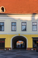 Facade of ancient house with archway and orange tiled roof on the street in a Sibiu city, Romania