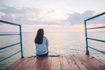 woman sitting alone on the pier and enjoing the view