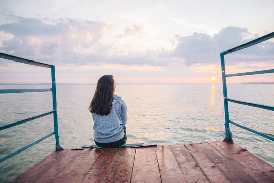 woman sitting alone on the pier and enjoing the view