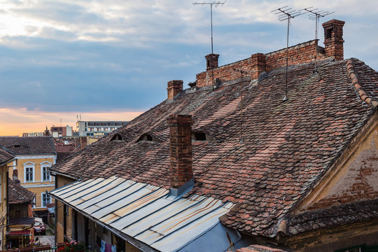 Architectural details and house roofs with attic windows designed in eyes shape in Sibiu city at sunset time, Romania