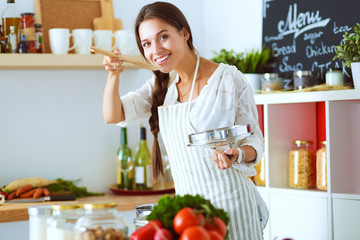 Cooking woman in kitchen with wooden spoon