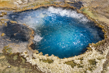 Hot spring, pool with boiling water in Yellowstone National Park. Closeup of a spring geyser. Blue boiling water.