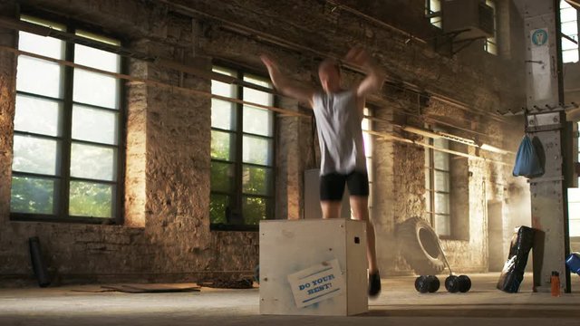 Muscular Shirtless Fit Man Energetically Box Jumps in Hardcore Gym doing Part of Cross Fitness Training Program