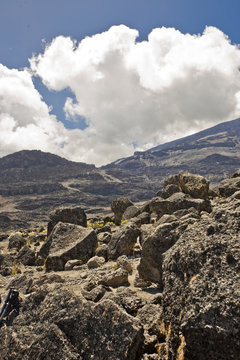 Mountainside of Mt. Kilimanjaro in Africa during the day with clouds overhead.