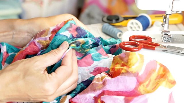 Seamstress touching colorful, silk material in the studio

