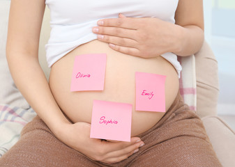 Pregnant woman with paper stickers on tummy, closeup. Concept of choosing baby name