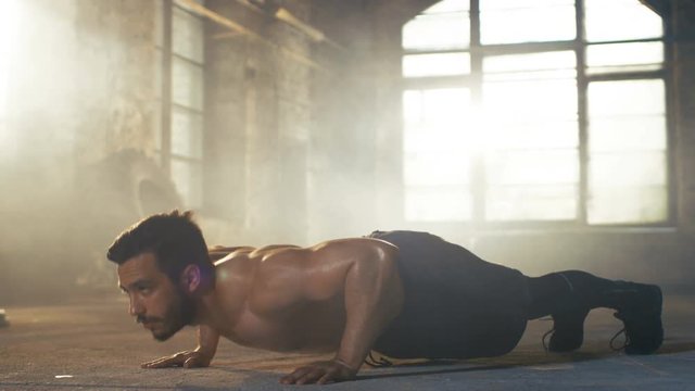 Muscular Shirtless Man Covered in Sweat Does Push-ups in a Deserted Factory Remodeled into Gym. Part of His Cross Fitness Workout/ High-Intensity Interval Training. 