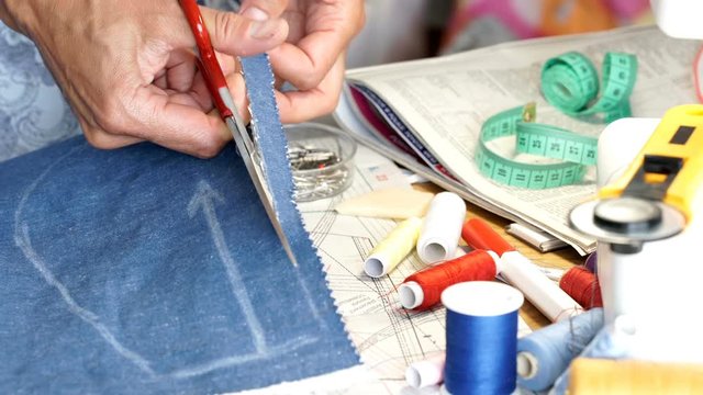 Seamstress using scissors and cutting the fabric
