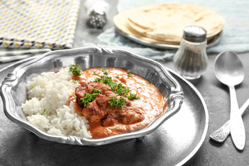 Plate with delicious Murgh Makhani and rice on table
