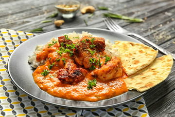 Plate with delicious Murgh Makhani and rice on table