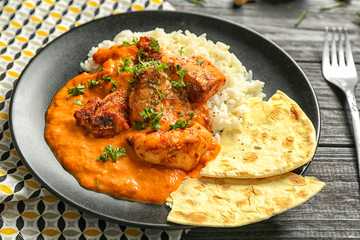 Plate with delicious Murgh Makhani and rice on table