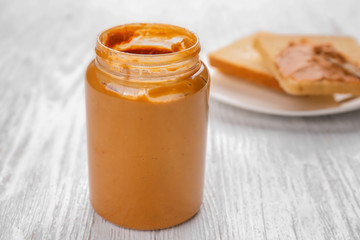 Jar of delicious peanut butter on white wooden table