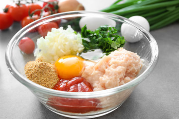 Glass bowl with ingredients for delicious turkey meatballs on grey table