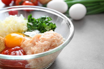 Glass bowl with ingredients for delicious turkey meatballs on grey table