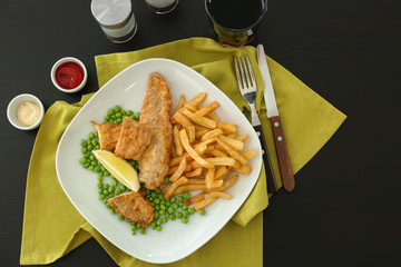 Plate with tasty fried fish and chips with peas on table