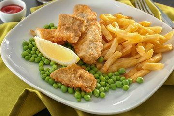 Plate with tasty fried fish and chips with peas on table
