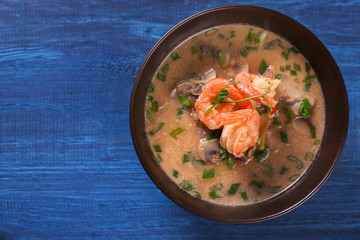 Delicious soup with shrimps in bowl on wooden background