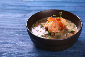 Delicious soup with shrimps in bowl on wooden table