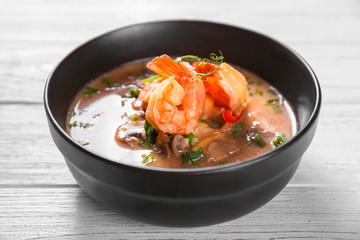 Delicious soup with shrimps in bowl on wooden table