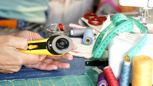 Seamstress holding rotary cutter and showing sharp blade to the camera
