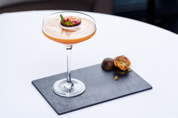 Cold cocktail with passion fruit on stone background.