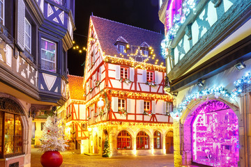 Traditional Alsatian half-timbered houses in old town of Colmar, decorated and illuminated at christmas time, Alsace, France - obrazy, fototapety, plakaty