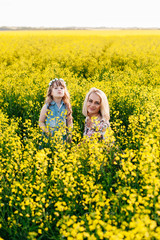 Mom and child having fun in a yellow flowering field