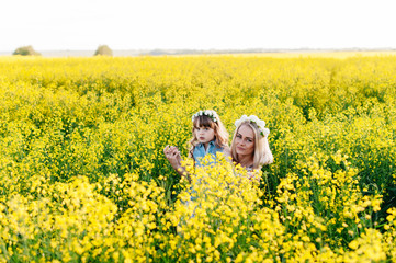 Fototapeta premium Mom and child having fun in a yellow flowering field